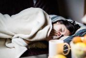 Frau mit Grippe liegt im Bett, das Taschentuch vor der Nase Frau mit Grippe liegt im Bett, das Taschentuch vor der Nase